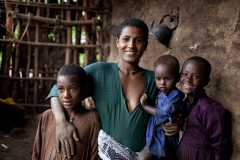 Balaynesh Kasa 27, a female farmer and beneficiary of the Debre Yacob Learning Watershed Restoration Project in Bahir Dar, Ethiopia. Photographed with her avocado trees, animals, beehives and waterpump and her 4 children
Eyrus 12, Ambtebal 9, Berekt 6 and Asmara 1 and a half yrs.
She says, “What we got from the project was the plants - 8 years ago, banana plants, avocado plants and hops
Before we had nothing.
When the project supported us we got all this benefit, for example the bananes, the kids eat them and I can sell them in the market, the hops I sell and I buy all the merchandise for the house like coffee, pepper, onions, oil, salt, meat, clothes for the kids, I can buy Medicines when they are sick, i buy all this just by selling the hops. In the past we struggled a lot. Now I can support my family and spend time with my kids (before I was sat in the market every day as a small trader) and I am so happy with this support, it has changed my life and I am so happy. All my kids can go to school now whereas before I might only have been able to send one. I would love my kids to be doctors and go further than I did.
I also have a beehive and a water pump.”