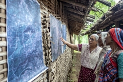 Farmers looks at sattelite images printout of Kanji village before CFR rights 2009 & after CFR rights in 2017  to see how their villages forest cover is improved after their practices after the village meeting in Sagai village.