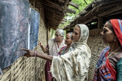 Farmers looks at sattelite images printout of Kanji village before CFR rights 2009 & after CFR rights in 2017  to see how their villages forest cover is improved after their practices after the village meeting in Sagai village.